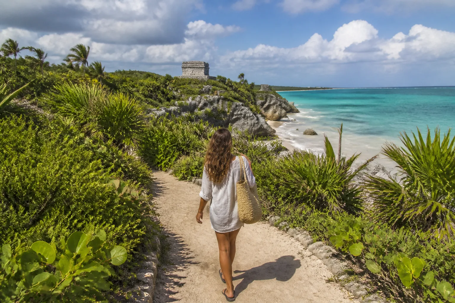 Visitor following a sandy access path toward a Tulum beach