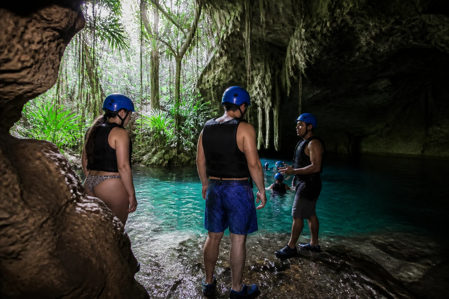 Travelers preparing with a guide at a water-filled cave entrance